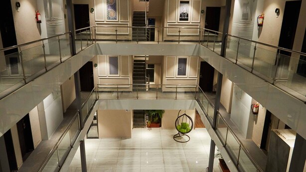 A multi-level atrium with glass railings, a central seating area, and a motivational quote on the floor. - Aureole Mrida (Mawal)