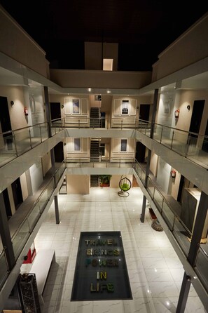 A multi-level atrium with glass railings, a central seating area, and a motivational quote on the floor.