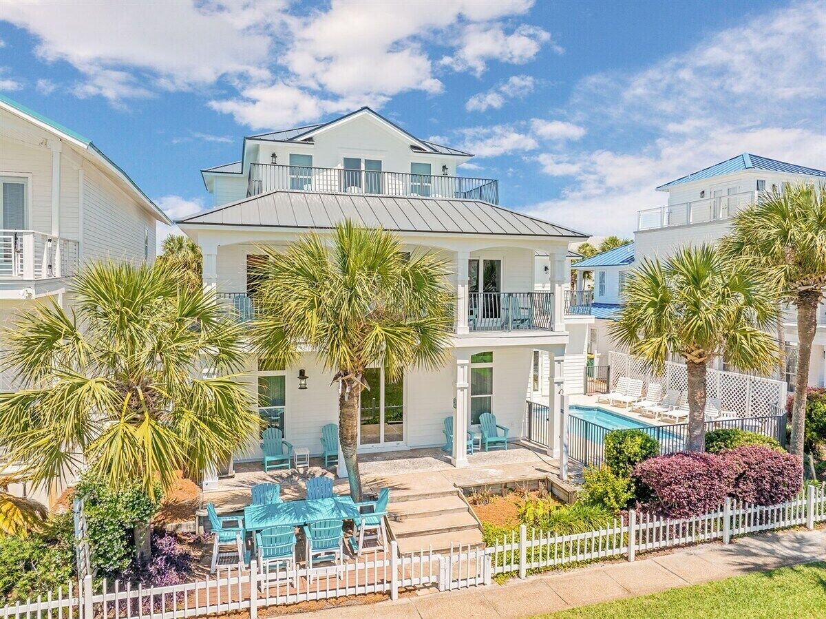 A two-story residential building with a balcony, a pool, and outdoor seating.