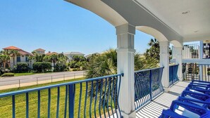 Un balcón con barandas azules que da a una zona residencial con casas y una calle.