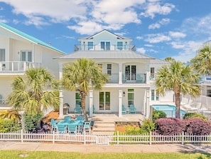 A two-story house with a balcony, outdoor seating, and a pool.