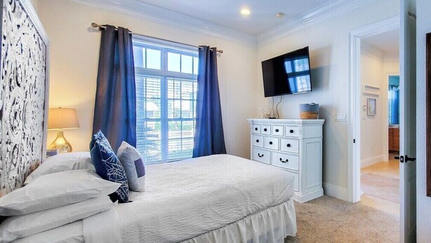 Un dormitorio con cama, cómoda, televisor y ventana con cortinas.