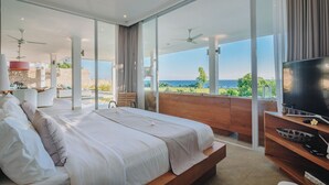 Un dormitorio con una cama grande, televisión y balcón con vista al océano.