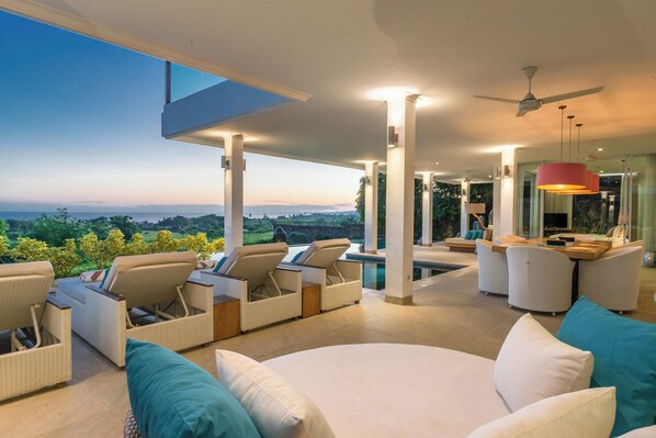 Ein moderner Außenbereich mit Korbmöbeln, einem Pool und Blick auf die Landschaft.