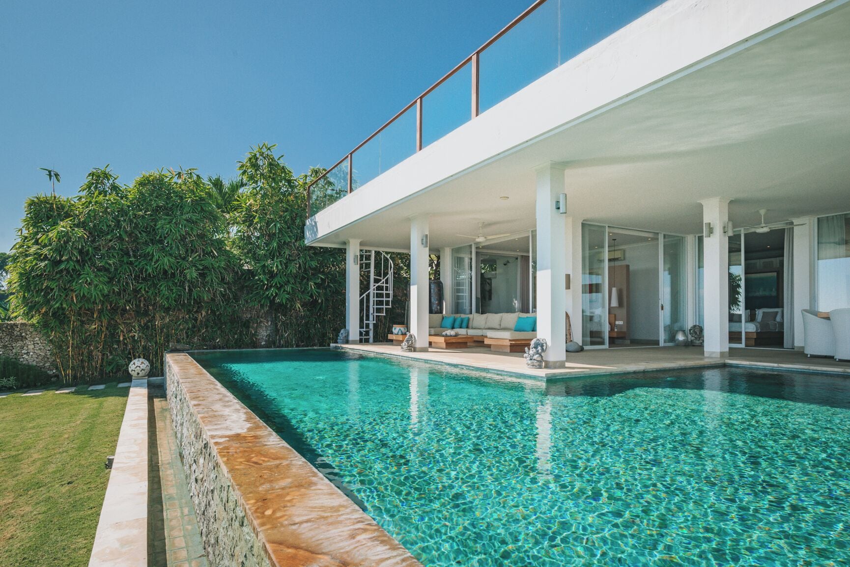 A modern house with a swimming pool, a covered outdoor seating area, and a view of the surrounding greenery.