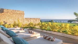 Una terraza en la azotea con sillones de descanso y un muro de piedra.