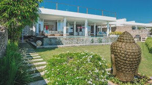 Una casa moderna con piscina, paredes de piedra y una gran escultura decorativa.
