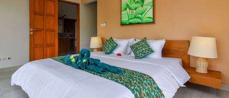 A hotel room with a large bed, two bedside lamps, a wooden nightstand, and a green and white patterned blanket.