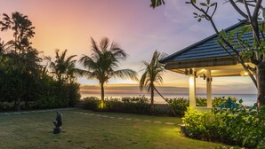 A tranquil garden with a gazebo overlooking a body of water, surrounded by palm trees and lush greenery. - Villa Saneva (Seririt)