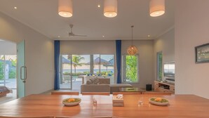 A modern dining area with a large wooden table, two ceiling fans, and a view of the outdoors. - Villa Saneva (Seririt)