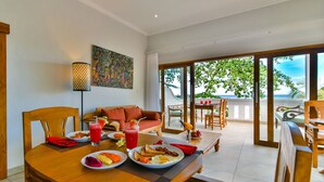 Un coin repas avec une table mise pour le petit-déjeuner, un canapé et un tableau accroché au mur.