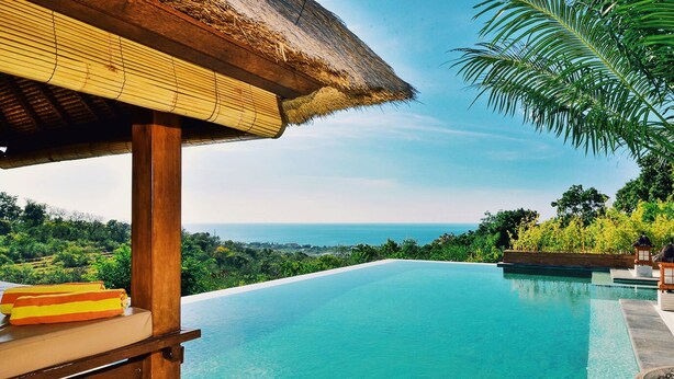 Ein Infinity-Pool mit Blick auf das Meer und üppige Vegetation.