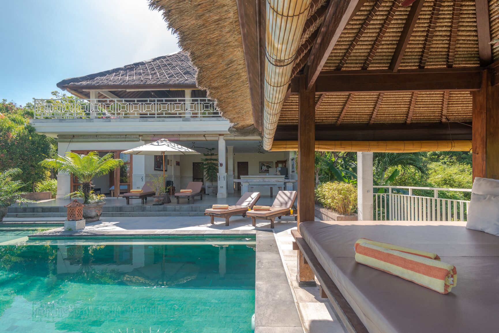 A resort with a swimming pool, lounge chairs, and a covered patio area.