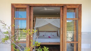 Ein Schlafzimmer mit Baldachinbett, Blick ins Freie und einem Balkon mit Geländer.