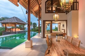 A luxurious villa with a private pool, a dining area with wicker furniture, and a bedroom with a large window overlooking the sea. - Villa Lakshmi (Banjar)