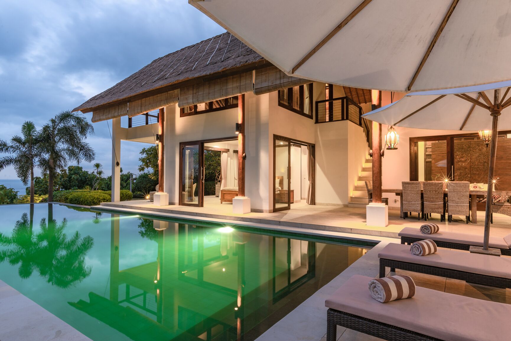 A modern house with a pool, outdoor seating, and a staircase leading to a balcony.