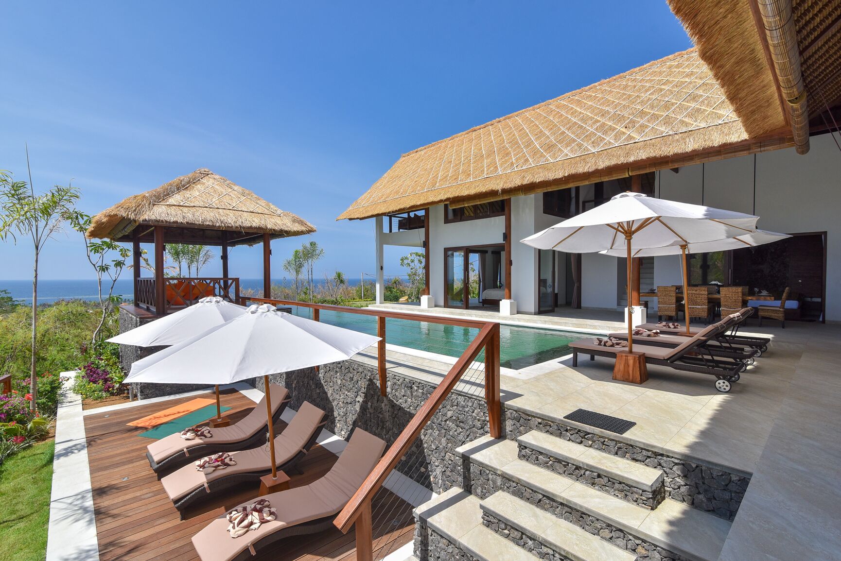 A resort with a pool, sun loungers, and thatched-roof structures.