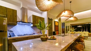 Una cocina moderna con encimera de mármol, electrodomésticos de acero inoxidable y una isla central con planta y frutero.