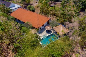 An aerial view of a house with a red-tiled roof, a swimming pool, and surrounding vegetation. - Villa Udara (Sukasada)