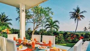 An outdoor dining area with a table set for two, surrounded by lush greenery and palm trees. - Villa Zoubi Bali (Seririt)