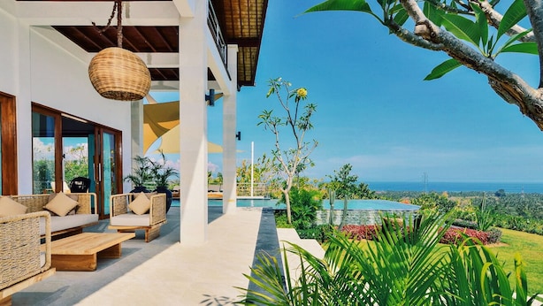 A modern outdoor living area with wicker furniture, a pool, and a view of the ocean. - Villa Sentosa (Sukasada)