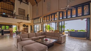 A spacious living area with a large sectional sofa, a coffee table, and a balcony with a view. - Villa Bali Il Mare (Gerokgak)