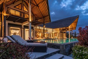 Een luxe villa met een zwembad, buitenzitplaatsen en een overdekt terras.