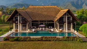 A resort with a pool, lounge chairs, and a mountain backdrop. - Villa Bali Il Mare (Gerokgak)