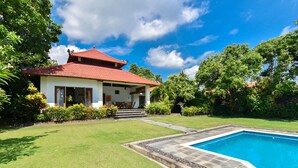 Une maison avec une piscine, entourée d’une pelouse bien entretenue et d’une végétation luxuriante.