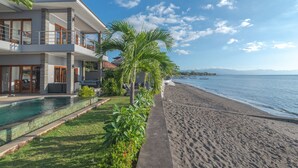Une maison moderne à deux étages, dotée d’une piscine, offrant une vue sur la plage et comprenant un jardin bien entretenu.