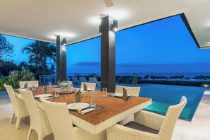 Ein Essbereich mit einem Tisch für vier Personen, mit Blick auf einen Pool und den Ozean.