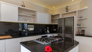 A modern kitchen with a central island, stainless steel appliances, and white cabinetry. - Villa Pondok Wahyu Sedana (Seririt)
