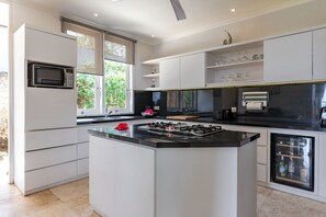 A modern kitchen with a central island, built-in microwave, and a wine fridge. - Villa Pondok Wahyu Sedana (Seririt)