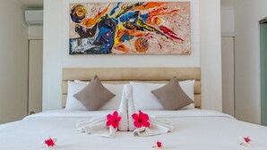A neatly made bed with white linens, two pillows, and a floral arrangement. - Villa Pondok Wahyu Sedana (Seririt)