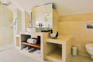 A modern bathroom with a glass-enclosed shower, a large mirror, and a built-in sink with a shelf for towels.