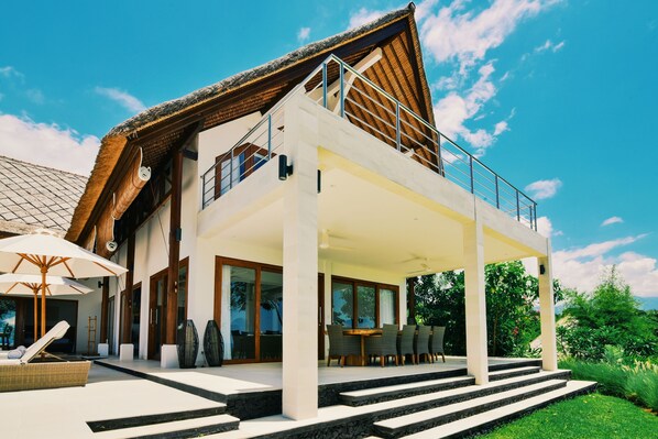 A modern two-story house with a balcony, large windows, and a well-maintained garden.