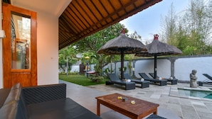 Une terrasse avec une piscine, des chaises longues et une table en bois.