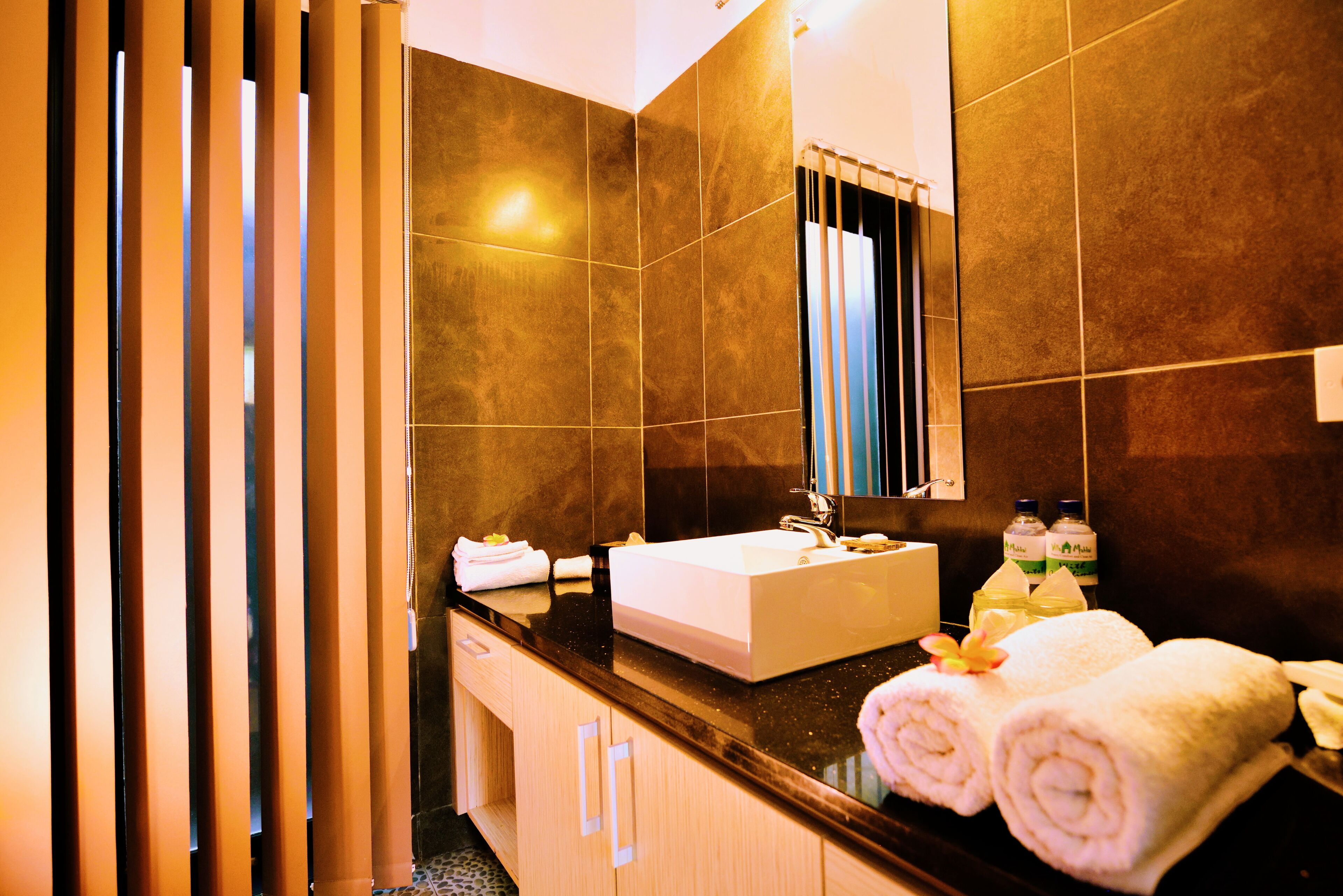 A modern bathroom with a large mirror, a white sink, and two towels on the counter.