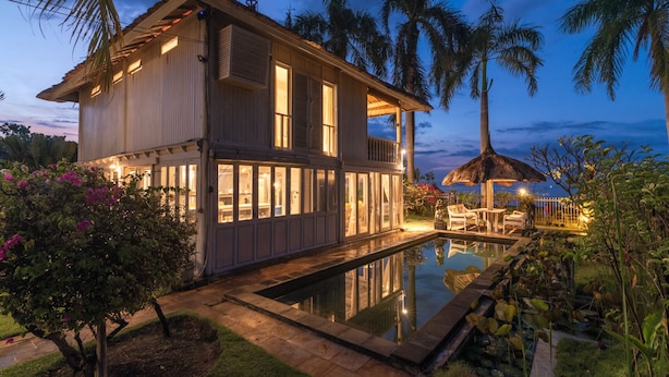A two-story house with a swimming pool, surrounded by palm trees and lush greenery. - Villa Lumbung (Sukasada)