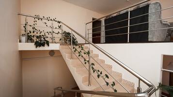 A staircase with metal railings, beige tiles, and potted plants.