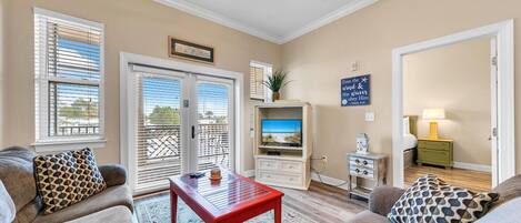 A living room with a red coffee table, beige sofas, and a TV.