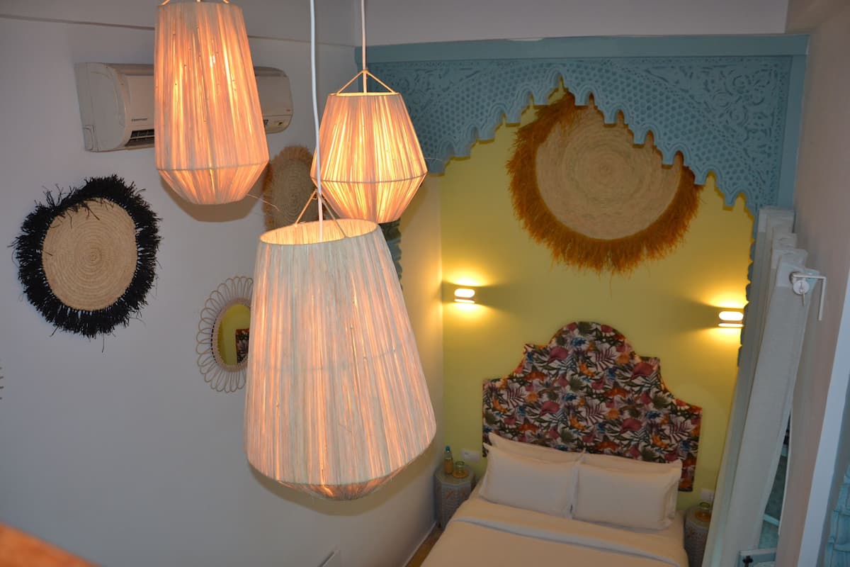 A bedroom with a bed, hanging lamps, and decorative wall hangings.