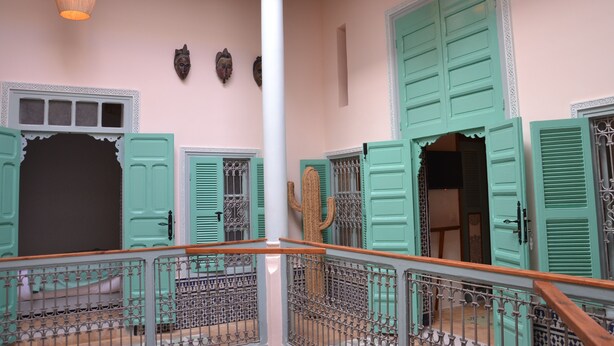 A spacious interior with high ceilings, a central column, and a staircase with ornate metal railings. - Riad Louane (Rabat)