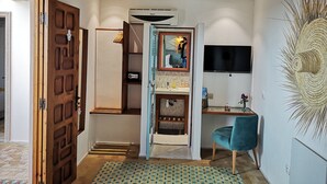 A modern interior with a wooden door, a mirror with a decorative frame, a mounted TV, and a decorative wall piece. - Riad Louane (Rabat)