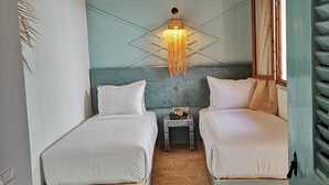 A bedroom with two beds, a patterned floor, a decorative wall light, and a wooden ceiling. - Riad Louane (Rabat)