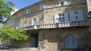 A stone building with a balcony and a door with decorative glass panels.
