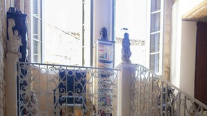 A stone staircase with ornate metal railings, a potted plant, and a Buddha statue.