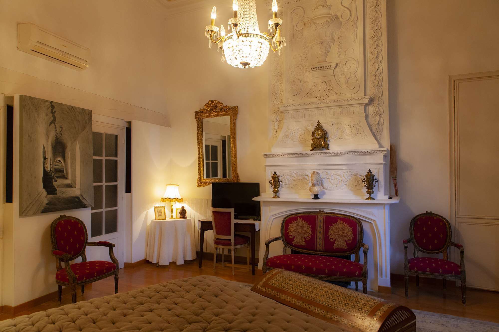 A luxurious room with a large bed, ornate fireplace, and classic furniture.