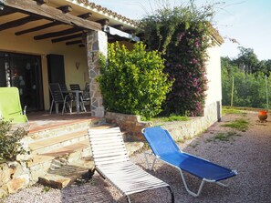 Un patio cubierto con muros de piedra, techo de madera y una zona de estar con dos sillones reclinables.