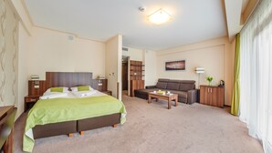 Een hotelkamer met een bed, een slaapbank, een salontafel, een kast en een schilderij aan de muur.